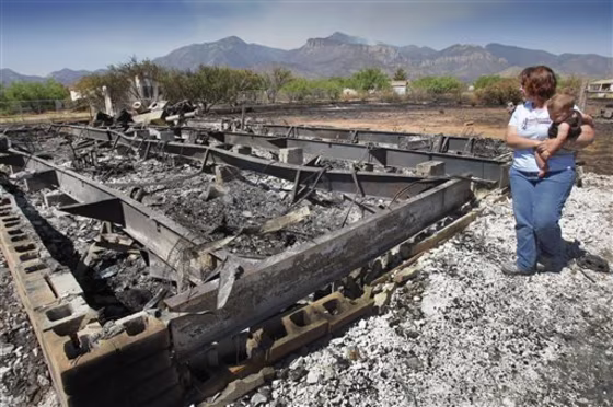 Gayle Gehr along with grandson Nathan Jacob look at their burned home that was destroyed from the Monument Fire near Sierra Vista, Ariz. on Wednesday.